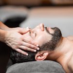 Man-lying-on-his-back-getting-his-forehead-massaged