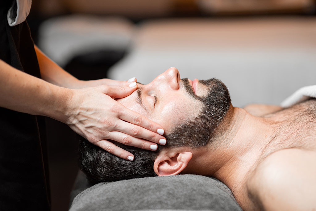 A man lies on his back during a craniosacral massage in Springfield, MO, used to treat TMJ without surgery at Precision Wellness