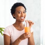 Smiling-woman-drinking-a-healthy-beverage-with-a-straw