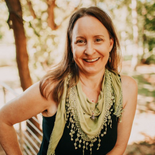 Christine Moses, yoga instructor at Precision Wellness, smiling outdoors wearing a green scarf and black top.