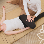 woman lying on a mat doing thai massage with therapist