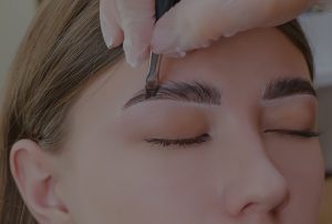 A woman recieves a eyebrow lamination treatment in Springfield, MO, as a gloved practitioner from Precision Wellness touches her face with a small brush to laminate the eyebrows.