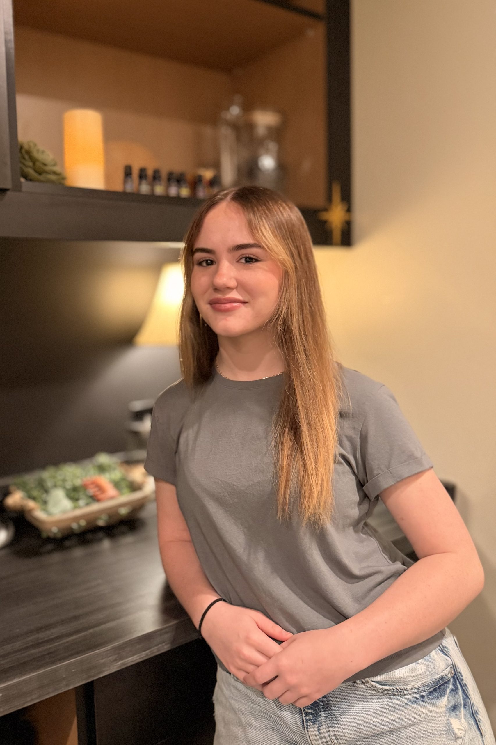 Eowyn Hancock, esthetician at Precision Wellness, smiling in a treatment room with warm lighting.
