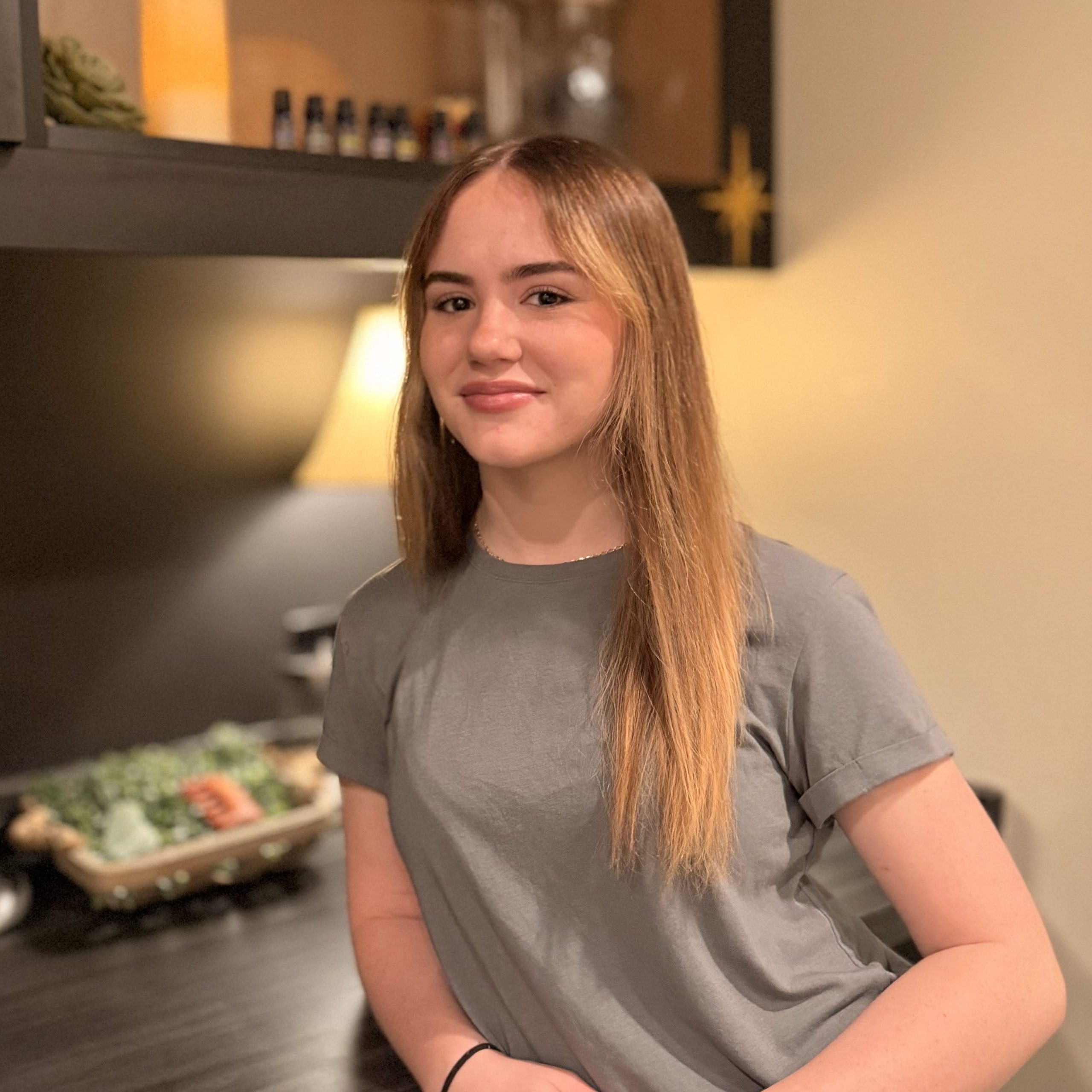 Eowyn Hancock, esthetician at Precision Wellness, smiling in a treatment room with warm lighting.