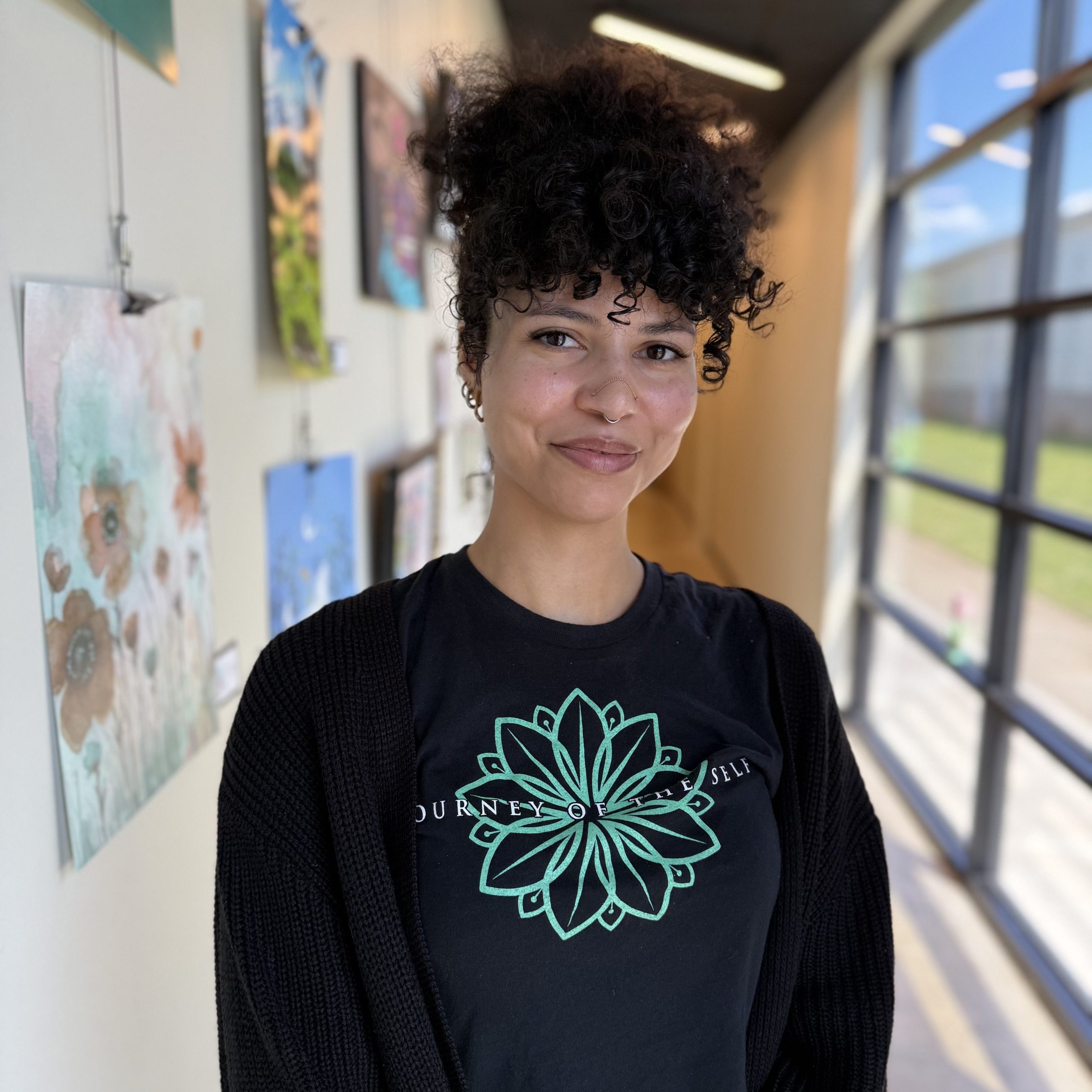 Maegan Wood at the Precision Wellness front desk, smiling in a bright hallway with artwork in the background.